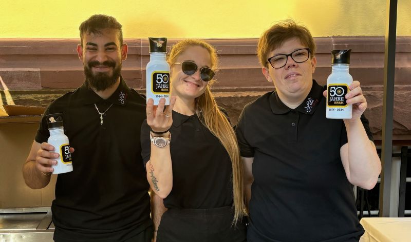 Erfrischend: Mitarbeiter:innen freuen sich über die Trinkflaschen mit dem Jubiläumslogo.